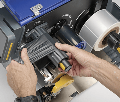 Een werknemer plaatst snel een nieuw printlint in een i7500-printer.