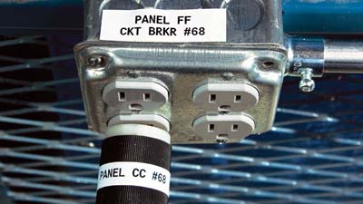 Multifunctionele vinyllabels van Brady aangebracht op een contactdoos en de stekker van een apparaat om aan te geven waarvoor ze worden gebruikt.